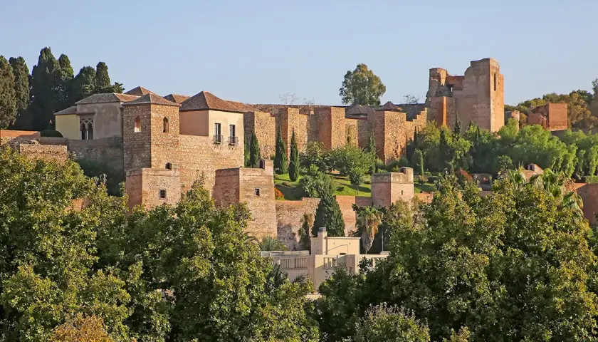 Malaga zamek, starożytna forteca z cegły i kamienia, wznosi się na wzgórzu pośród zieleni.