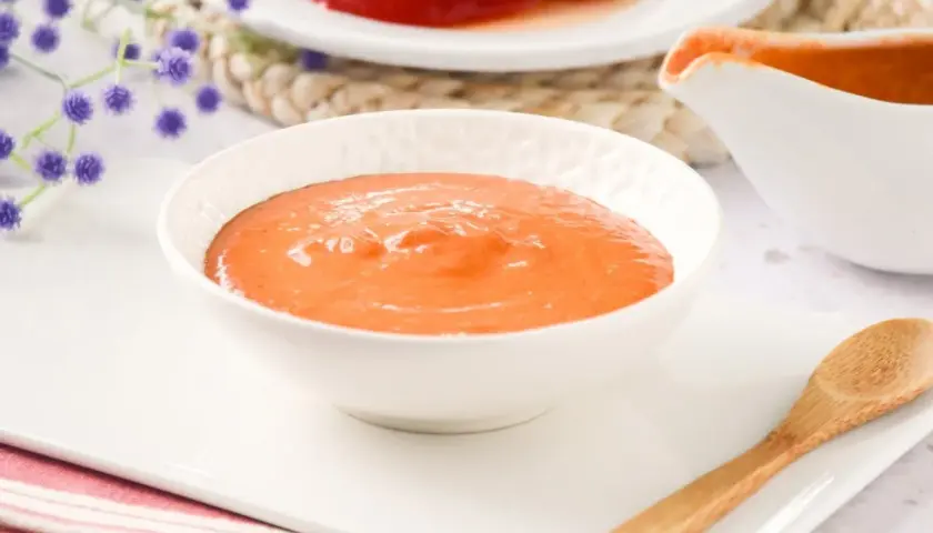 Un cuenco blanco lleno de cremosa salsa de pimientos del piquillo, lista para acompañar tus platos.