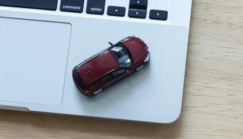 Czerwony samochodzik na laptopie. Zastanawiasz się, ile kosztuje wystawienie samochodu na OLX?
