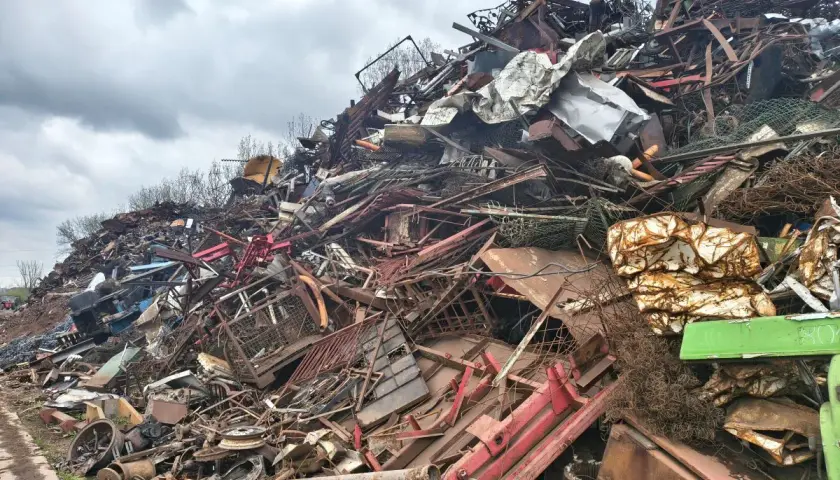 Góra złomu, gdzie można sprawdzić skup akumulatorów cena za kg. Widoczne różne rodzaje metali, siatki, części maszyn.