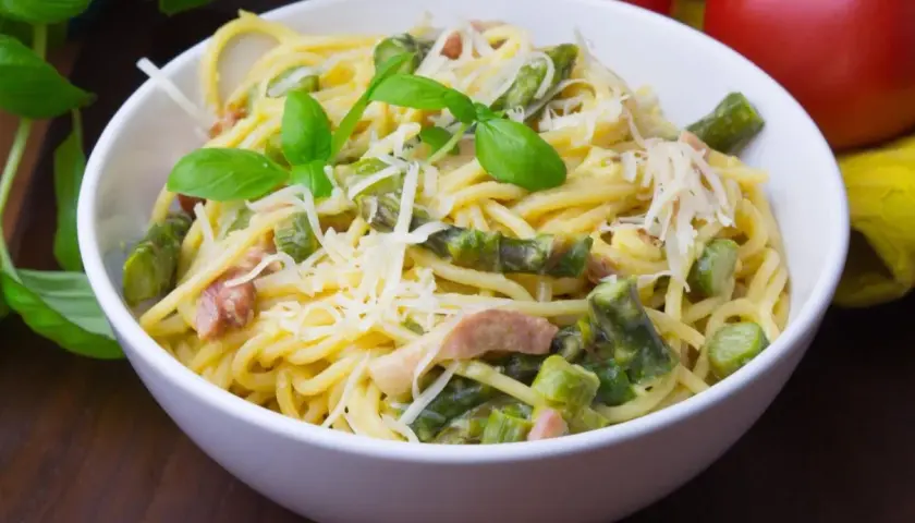Pyszna carbonara ze szparagami, udekorowana bazylią i parmezanem. Idealna na wiosenny obiad.