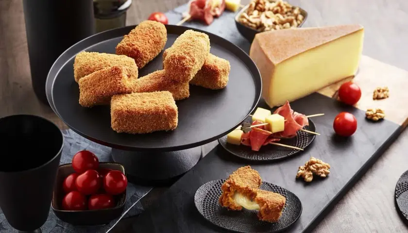 Croquettes dorées, garnies d'un fromage fondant, parfaites pour une raclette gourmande. Tomates cerises et noix accompagnent ce délice.