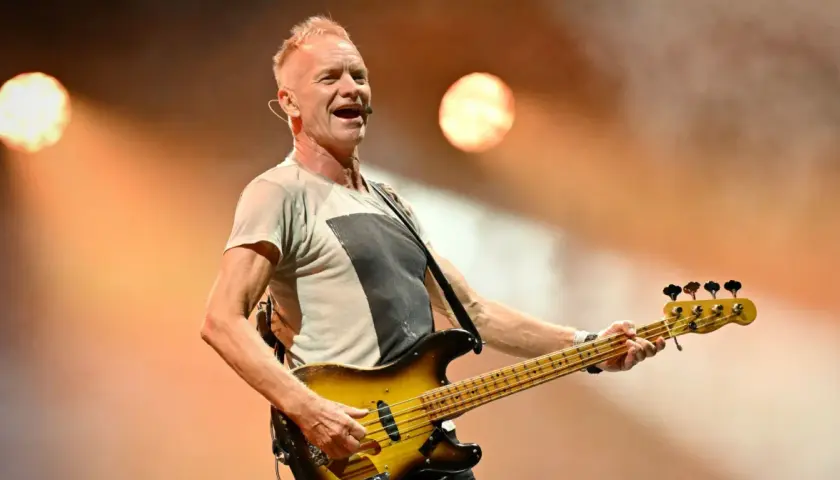 Wokalista The Police, Sting, gra na gitarze basowej podczas koncertu.