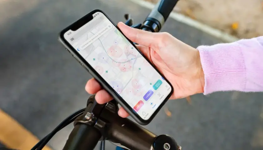 Aplikacja na rower iPhone pokazuje mapę z zaznaczonymi punktami. Użytkownik planuje trasę lub szuka miejsc.