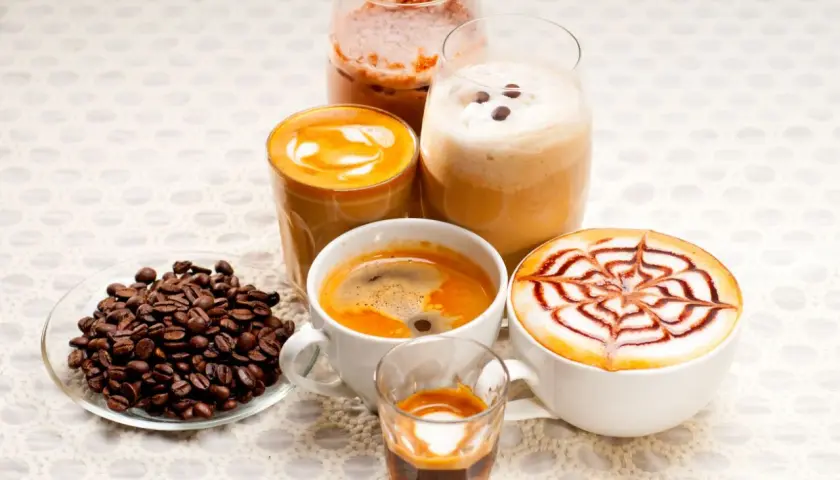 Różnorodne kawy, w tym latte z wzorem, espresso i napoje mrożone, idealne na keto dietę. Obok ziarna kawy.