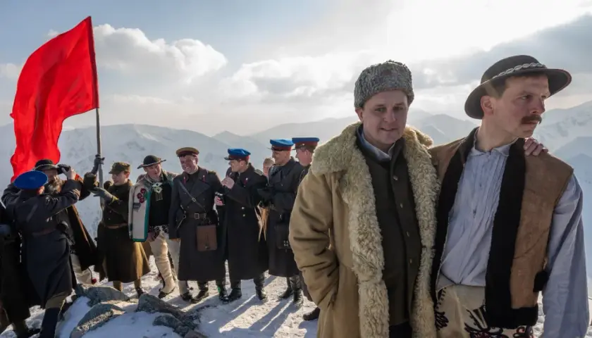 Grupa ludzi w strojach historycznych na tle gór. Czerwona flaga powiewa na wietrze. To może być scena z filmu, która zasługuje na biała odwaga recenzja.
