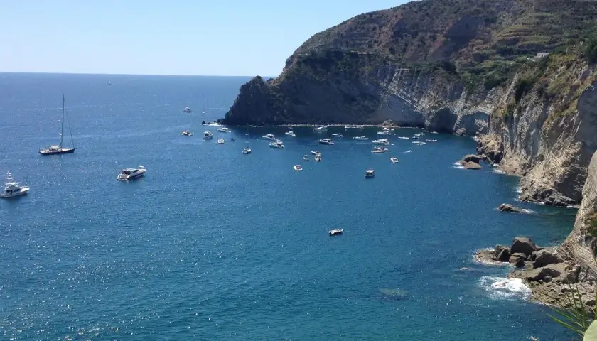 Baie de Sant'Angelo à Ischia, parsemée de bateaux sous un ciel bleu éclatant.