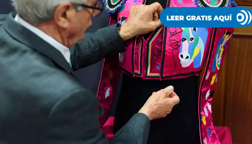 Un hombre ajusta un traje de luces rosa con caballos bordados, listo para una corrida en Madrid.
