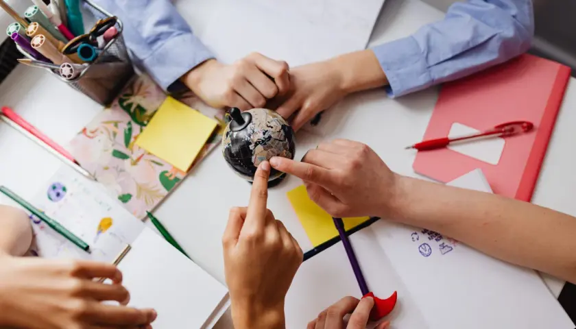 Kinder lernen an gruppentischen grundschule. Sie erkunden einen Globus und malen.