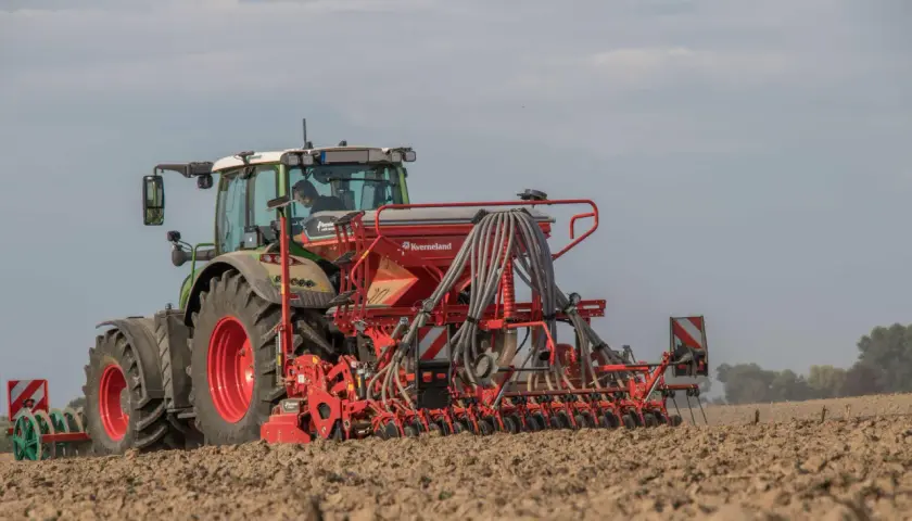 Traktor mit Sämaschine bei der Sommergerste Aussaat auf einem Feld.
