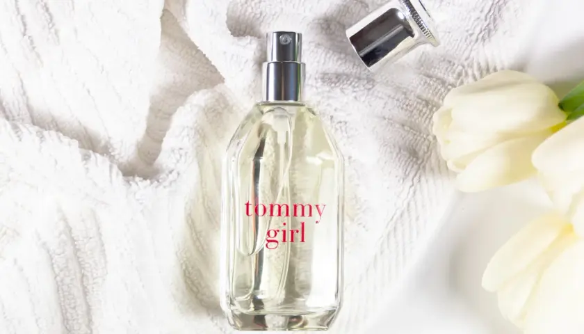 Tommy Girl Parfümflasche auf weißem Handtuch mit weißen Tulpen.