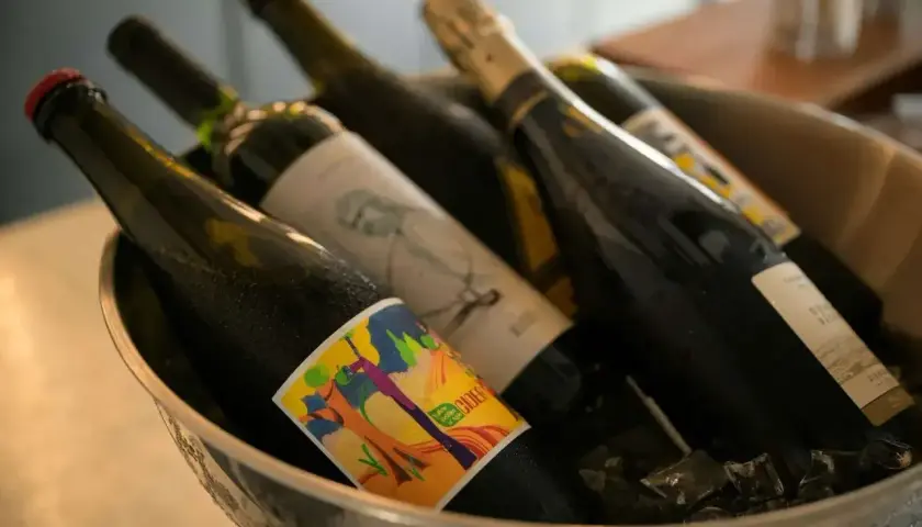 Butelki z winem w wiaderku z lodem. Zastanawiasz się, czy można przewozić alkohol w bagażu rejestrowanym? Sprawdź przepisy!