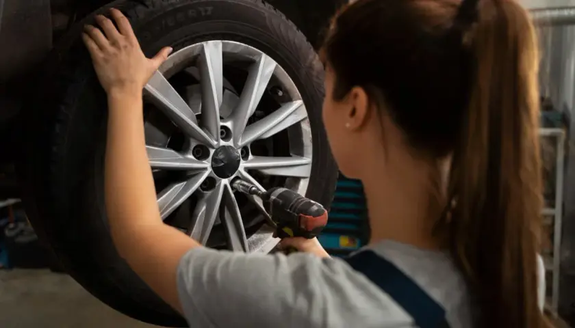 Mechanik używa klucza udarowego do kół, by dokręcić śruby w feldze.