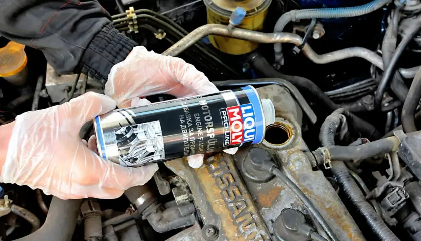 Ręce w rękawiczkach trzymają puszkę Liqui Moly Engine Flush, gotową do użycia w silniku.
