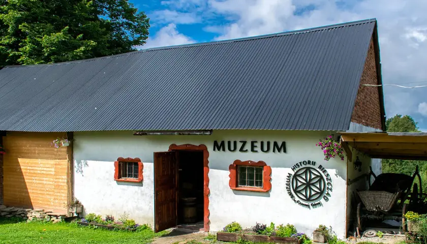 Muzeum w Bieszczadach zaprasza do odkrywania historii. Biały budynek z drewnianymi elementami i otwartymi drzwiami.