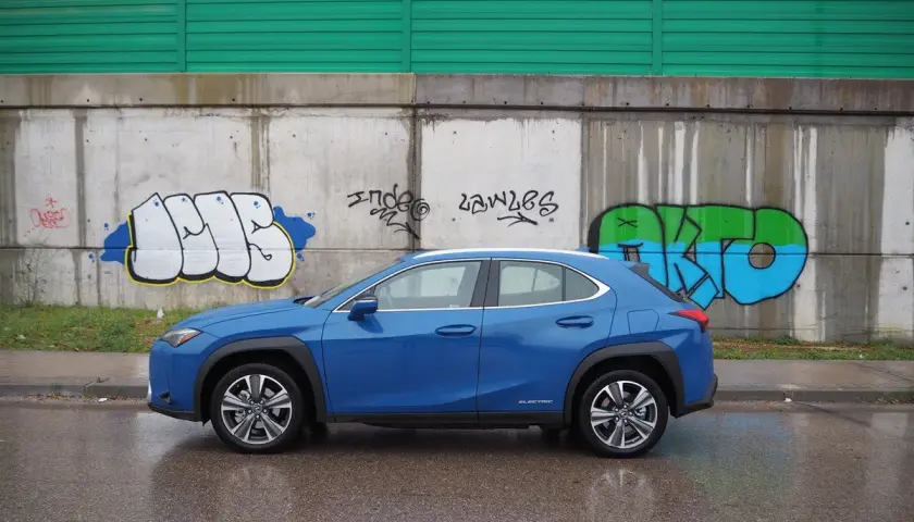 Lexus UX azul aparcado frente a un muro con grafitis. A pesar de los problemas, el coche eléctrico se ve elegante.