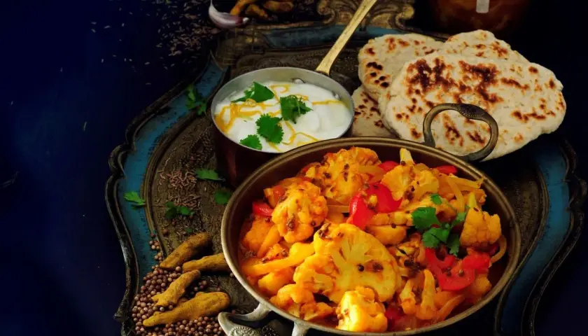 Aksamitne curry z kalafiora z mleczkiem kokosowym, podane z chlebkami naan i jogurtem.