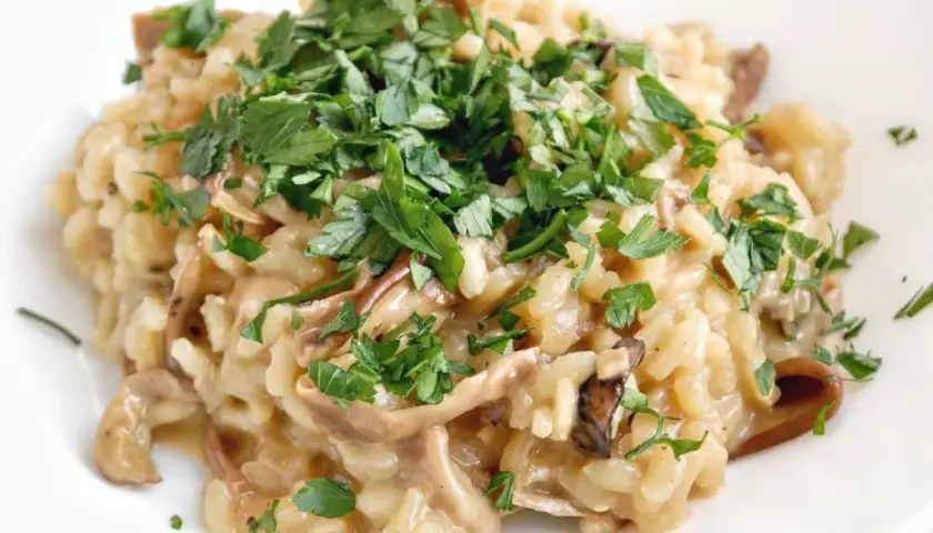 Kremowe risotto z grzybami, posypane świeżą natką pietruszki. Idealne na jesienny obiad.