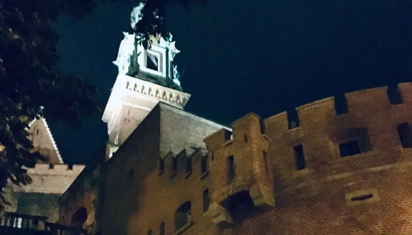 Wieczorne ciekawostki o Krakowie: Wawel nocą, z murami i wieżą oświetloną blaskiem księżyca.