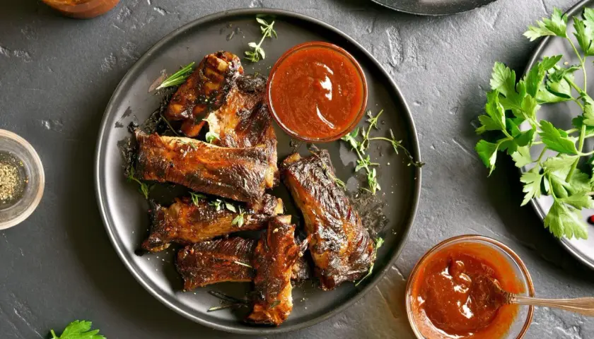 Soczyste żeberka pieczone na patelni, polane sosem BBQ. Aromatyczne zioła i świeża natka pietruszki dopełniają danie.