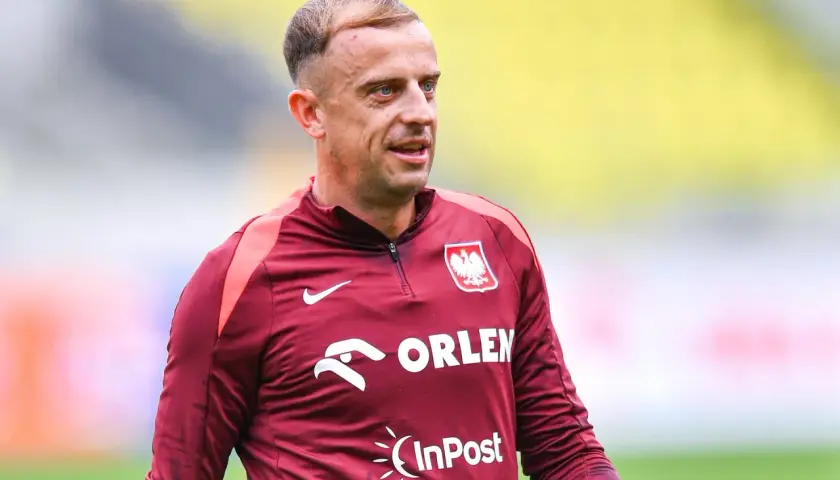 Piłkarz Kamil Grosicki w bordowej koszulce reprezentacji Polski z herbem i logo Orlen.