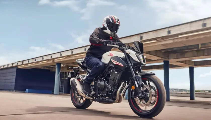 Hombre en moto Honda Hornet blanca y negra, con casco, acelerando. El motor de la moto ratea al acelerar, pero la experiencia es emocionante.