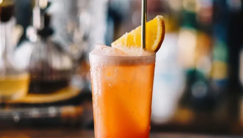 Orzeźwiający drink Garibaldi z plasterkiem pomarańczy i złotą słomką, idealny na letnie popołudnie.