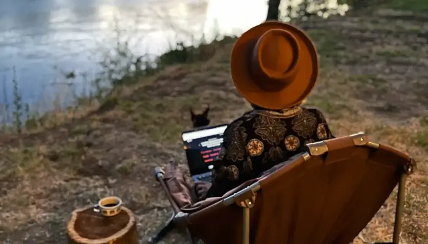 Praca zdalna nad rzeką. Kawa na pniu, piesek i laptop. Tak wygląda życie digital nomad co to znaczy?