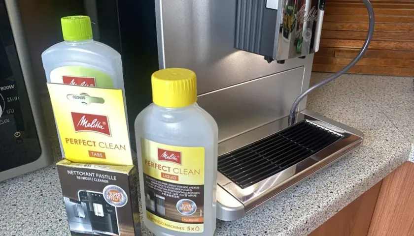 Płyn i tabletki Melitta Perfect Clean obok ekspresu. Idealne, by dowiedzieć się, jak odkamienić ekspres Dolce Gusto.