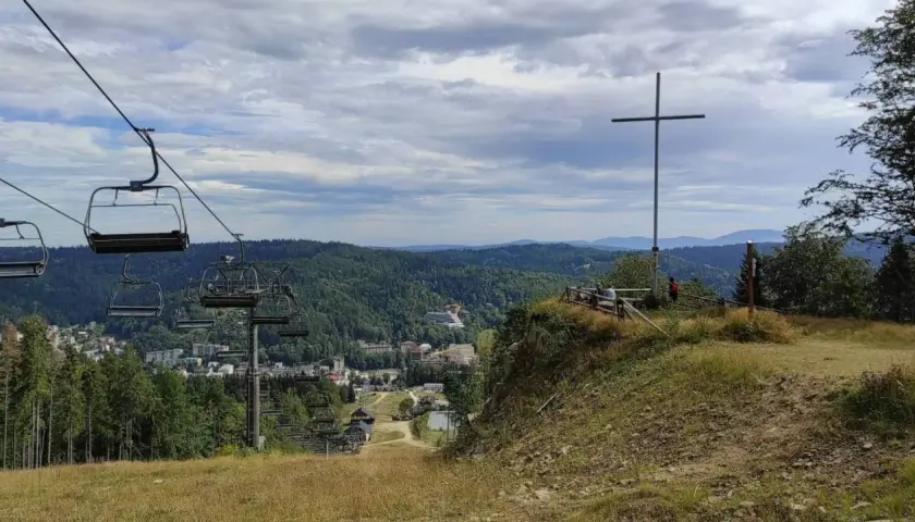 Widok z góry krzyżowej na dolinę z wyciągiem krzesełkowym i zabudowaniami.