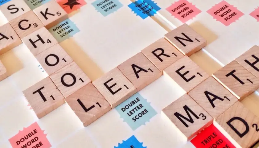 Litery na planszy do gry układają się w słowa "SCHOOL", "LEARN", "MATH". Czy angielski jest trudny? Zależy od tego, jak się uczysz!