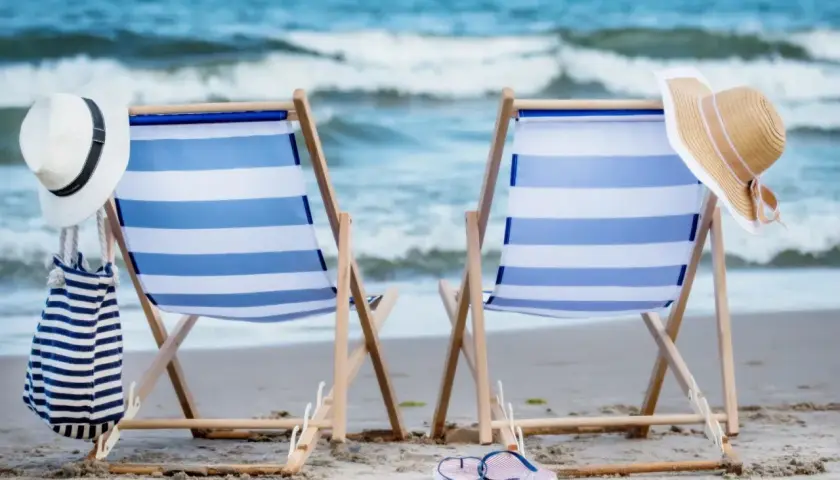 Dwa leżaki na plaży, gotowe na idealny weekend nad morzem. Słońce, szum fal i relaks czekają.
