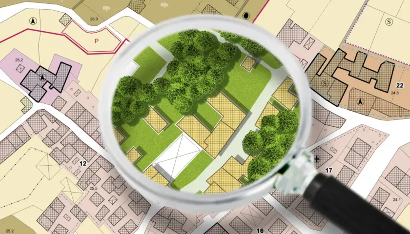 Plan d'urbanisme sous loupe, révélant des parcelles et des espaces verts. L'intérêt à agir en urbanisme est ici illustré par le détail des projets.