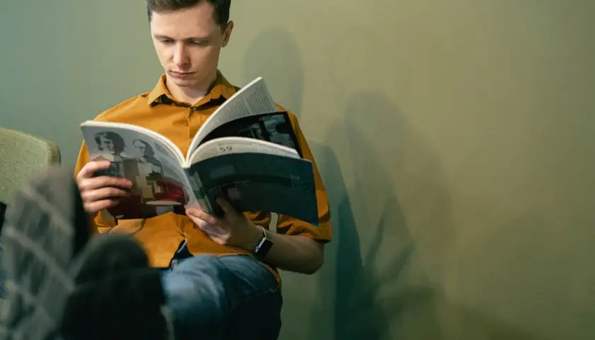 Młody mężczyzna czyta książkę, zastanawiając się, jakie książki z nurtu cli-fi warto przeczytać w 2026.