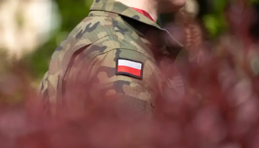 Żołnierz w mundurze moro z polską flagą na ramieniu, symbol służby i przyszłej emerytury policyjnej.