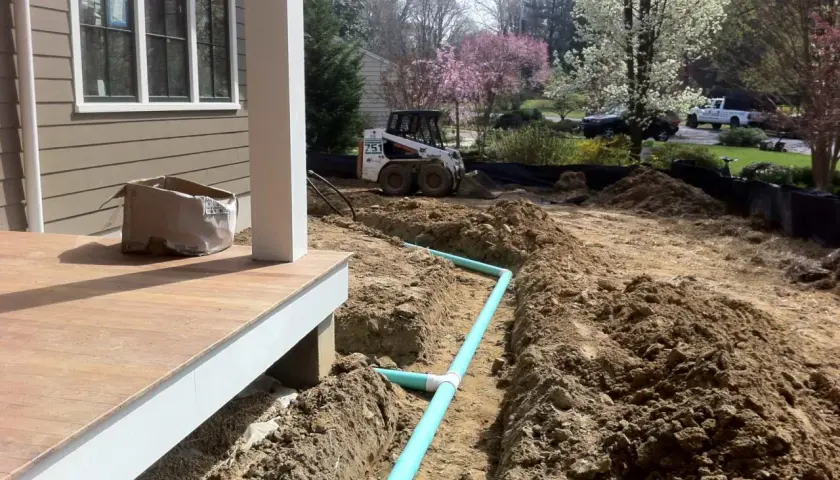 Bauarbeiten am Haus: Ein Bobcat-Lader und ein Bagger sind im Einsatz, um Rohre für die Drainage zu verlegen.
