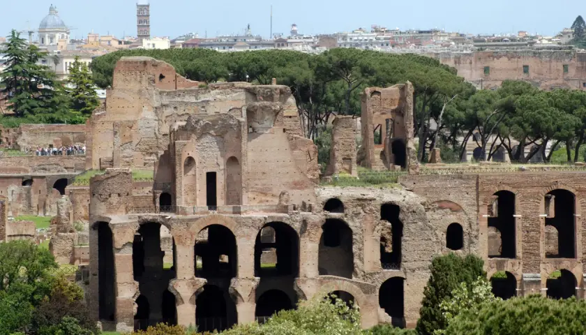 Antiche rovine del **Monte Palatino a Roma**, con archi imponenti e mura di mattoni che si stagliano contro il cielo azzurro.