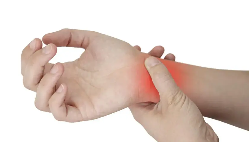 Una mano se presiona la muñeca, donde un área roja indica dolor por tendinitis.