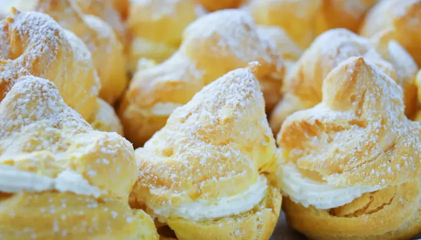 Choux garnis de crème, saupoudrés de sucre glace. Pour qu'ils restent gonflés, il faut bien cuire la pâte à choux et ne pas ouvrir le four trop tôt.