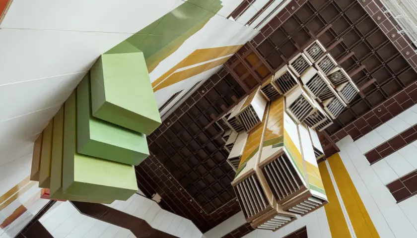 Geometryczne formy i kolory tworzą unikalną przestrzeń. Ta fotografia architektury ukazuje wnętrze z perspektywy od dołu.