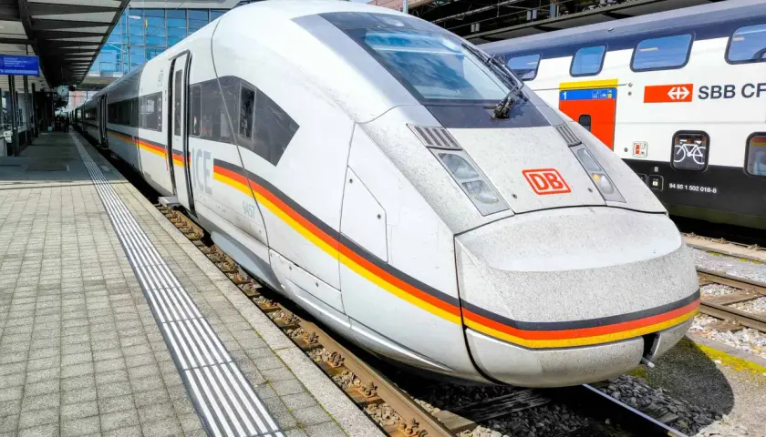 Moderner ICE train mit Deutschlandfarben am Bahnhof. Daneben ein SBB CFF FFS Zug.