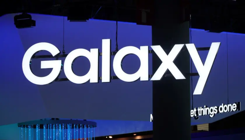Jasne, oto tekst alternatywny:

Duży, biały napis "Galaxy" na niebieskim tle. Pod nim mniejszy napis "et things done". W tle widać elementy wystroju, w tym niebieskie światła. To wszystko nawiązuje do technologii i innowacji, które chroni **Knox**.