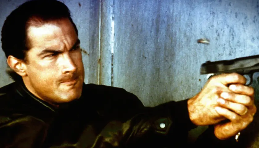 Steven Seagal jako Nico, policjant z filmu "Nico - ponad prawem", celuje z pistoletu.