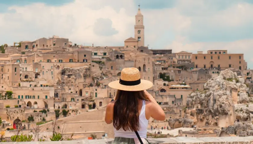 A woman in a straw hat takes in the ancient city of Matera, a highlight of any southern Italy trip itinerary.