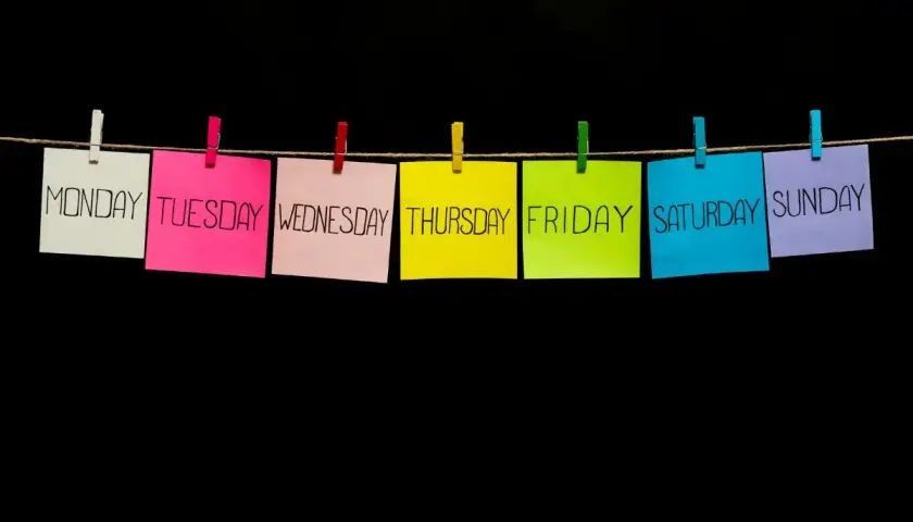Post-it colorati con i giorni della settimana appesi a un filo. Il giovedì in inglese, "Thursday", è su un foglio giallo.
