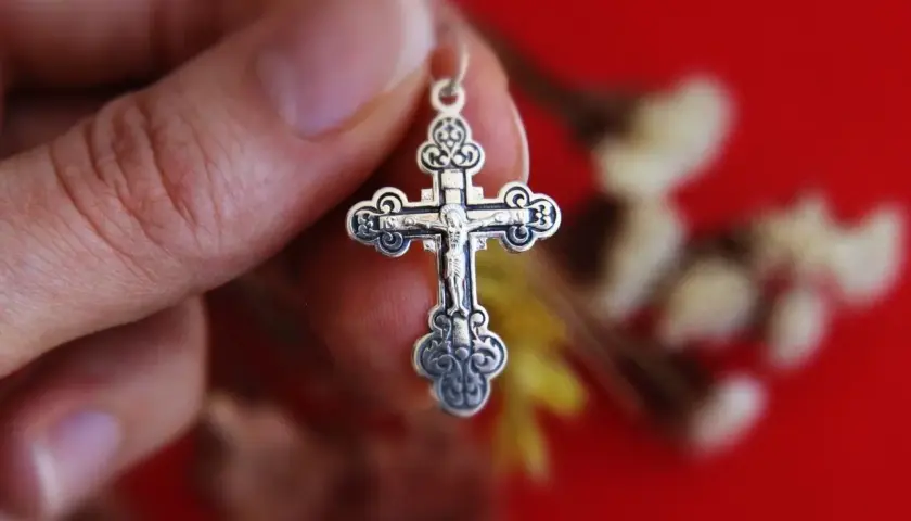 Srebrny krzyż prawosławny w dłoni. Różnice między prawosławiem a katolicyzmem mogą być widoczne w symbolice.