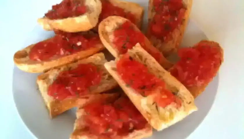 Des tranches de pain grillé garnies de tomates fraîches et d'herbes. Un délice simple et savoureux, parfait pour un apéritif.