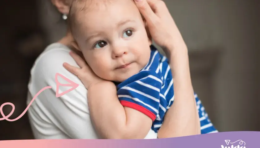 Ciepły uścisk mamy, kiedy dziecko zaczyna się przytulać. Maluch w pasiastej bluzeczce wtula się w jej ramię.
