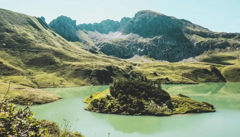 A serene lake reflects the rugged peaks of the Bavarian Forest. Perfect for **wandern im Bayerischen Wald**, this landscape offers a peaceful escape.