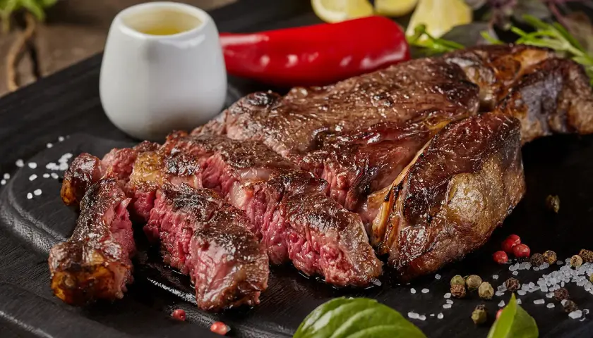 Une côte de bœuf parfaitement saisie, juteuse et rosée, prête pour la dégustation. La cuisson est idéale pour ce plat.